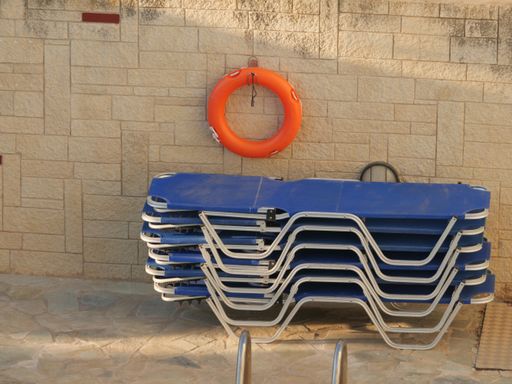A high angle shot of a stack of spine board stretchers and a floater hanging on the wall of the poolside