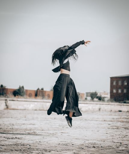 A dancer jumping in the air with black clothes on - concept of professional dancing and talent