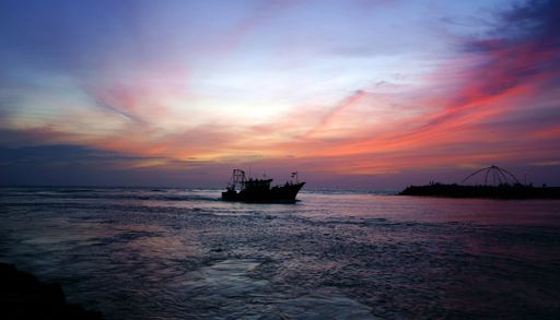 A breathtaking view of ship silhouette in the sea on red and blue sunset sky background