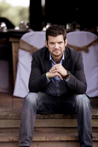 A vertical closeup shot of a well-dressed male sitting and looking at the camera
