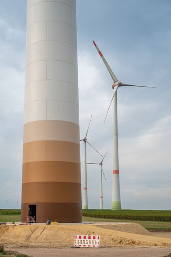 A vertical shot of a wind turbine at the construction site under blue cloudy sky