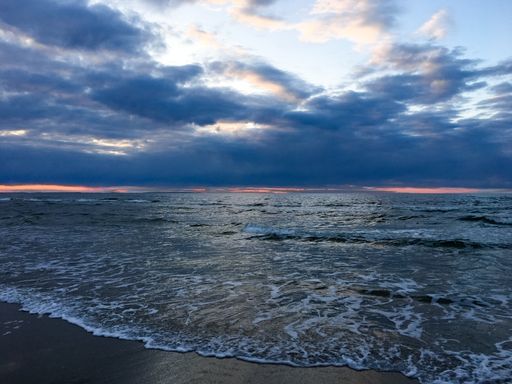 A breathtaking shot of the ocean under the cloudy sky during the sunset