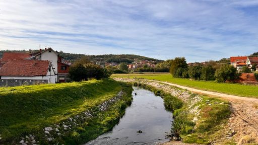 A scenic view of a river stream passing through a village with a beautiful mountain in the background