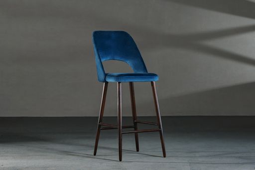 A blue dining room chair in a studio with gray walls