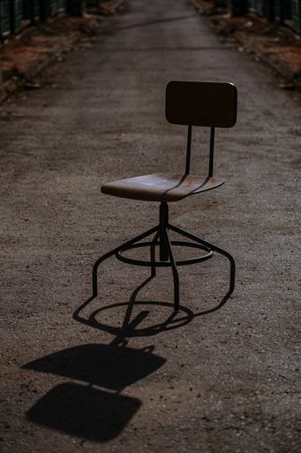 A vertical shot of a simple wooden chair on the ground with a blurry background
