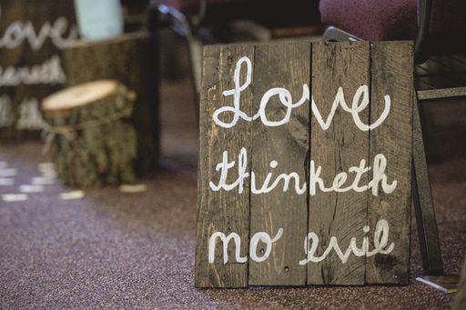 A closeup shot of a wooden sign with text written on it and a blurred background