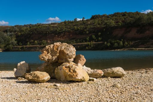 An unusual pile of large stones on the shore of the lake on a sunny day