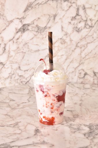A vertical shot of a strawberry milkshake on a marble surface