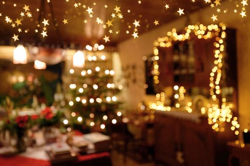 A bokeh photo of the festive living room's lights with a Christmas tree, decorations, a served table, and fairy lights