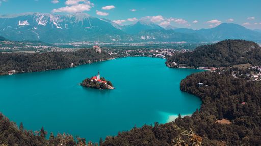 An aerial shot of the beautiful Lake Bled with the small Bled island surrounded by trees and mountains