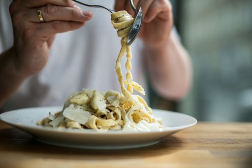 A selective focus shot of a male twirling delicious spaghetti on a fork
