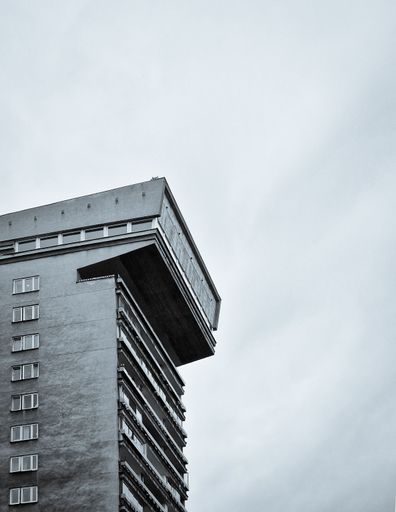 A vertical low-angle grayscale shot of the post soviet residential building in Warsaw on a cloudy day