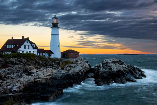 A scenic view of the Portland Head Lighthouse with a beautiful sunset visible in the background