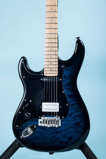 A vertical shot of black and dark blue electric guitar on a stand on light blue background
