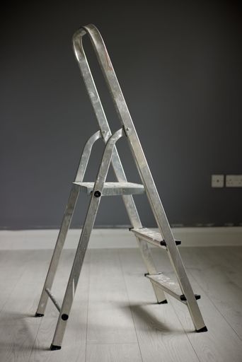 A metal ladder in the center of a gray room