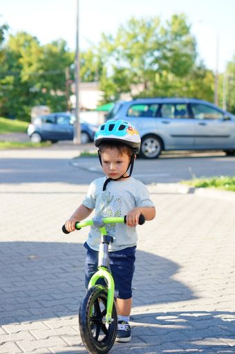 Young boy on a running bike wearing a safety helmet on a street
