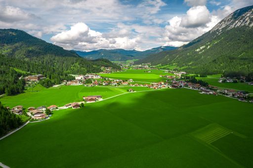 An aerial view of houses and buildings in lush green Tyrol, Austria between green mountains