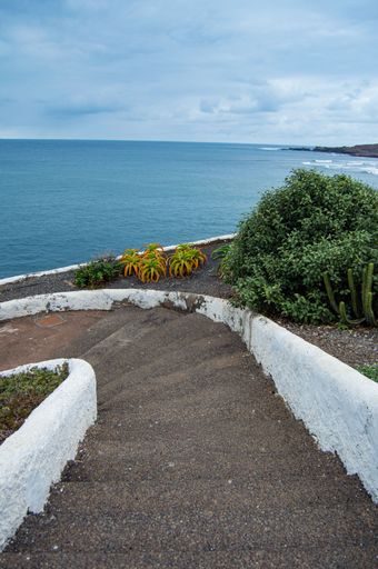 A vertical shot of rock stairs leading to the blue sea on a sunny day