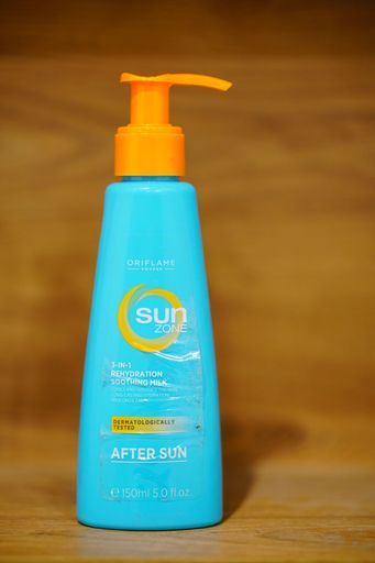 A vertical shot of a Sun Zone brand sun cream in a blue bottle