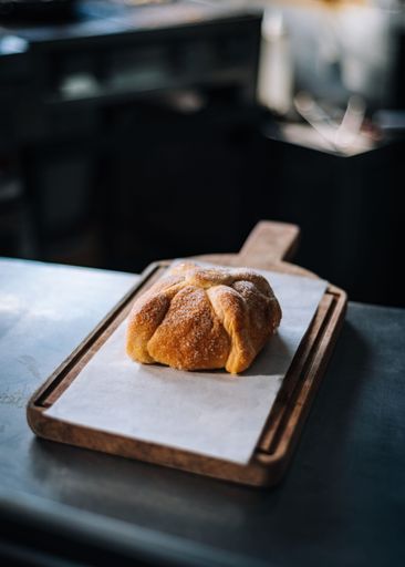 A vertical shot of the traditional Mexican Pan de muerto on a wooden board