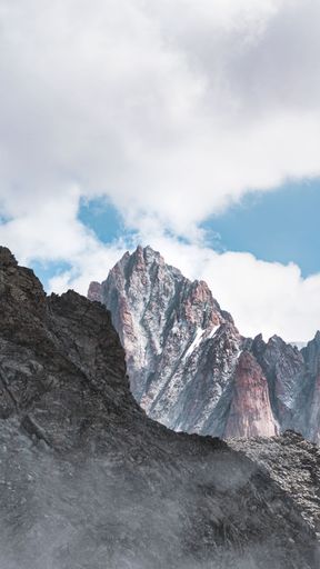 A vertical shot of the rocky mountains against the cloudy sky background