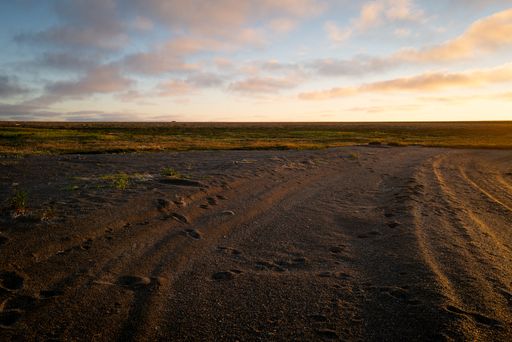A beautiful view of a sandy field under the cloudy sky during sunset