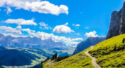 A breathtaking view of the fields and mountains under the beautiful clouds in the blue sky