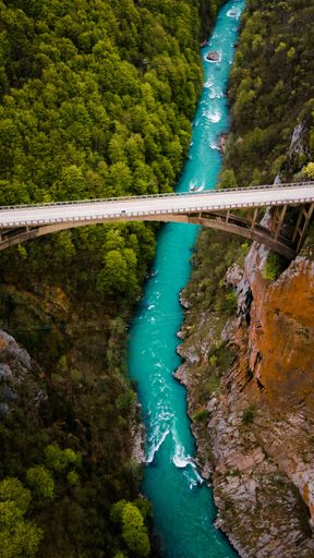 An aerial view of a narrow river crossing a gorge, and a bridge above it