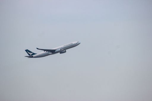 A white Cathay Pacific aircraft flying in the clear white sky