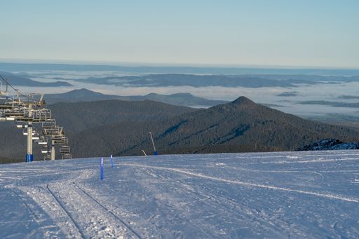 A beautiful ski resort with a chairlift and scenic forested mountains covered in fog in the distance