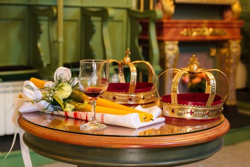 A selective focus shot of two crowns and a glass of wine for the orthodox wedding