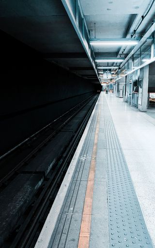 A vertical shot of a empty modern subway station platform with direction signs at night