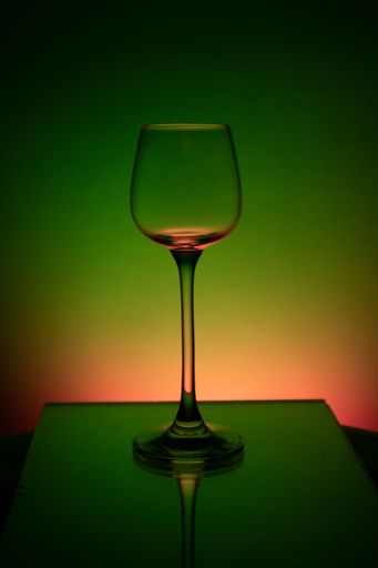 A vertical shot of an empty wine glass against a colorful background