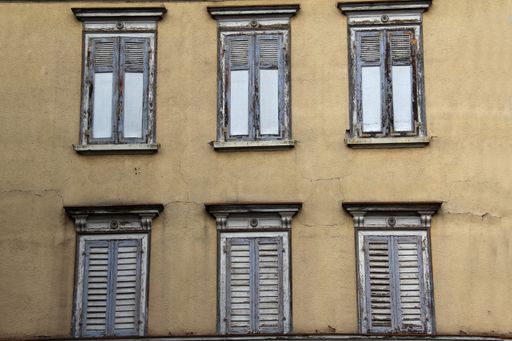 A low angle shot of closed windows on an old building