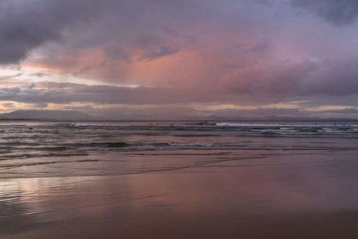 A beautiful soft pink sunset with fluffy clouds over the sea shore