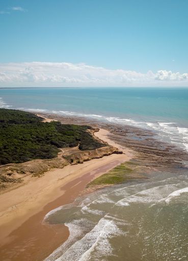 A vertical shot of a beautiful coastline on a bright sunny day