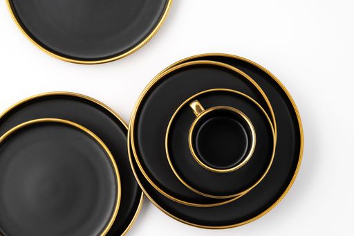 A set of black and golden ceramic plates and cup on a white background. Top view