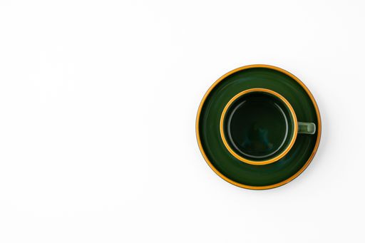 A set of green ceramic plate and coffee mug on a white background