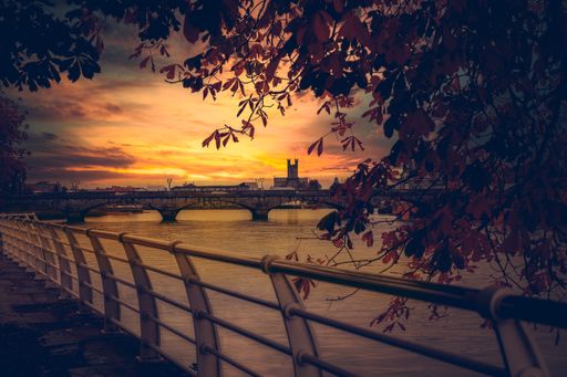 A scenic view of a bridge over a calm sea during sunset seen from a baywalk