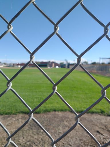 A metal link chain fence against a baseball field in the background in Colorado, USA