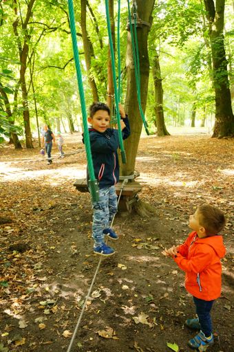 Child standing on a rope of a obstacle route at a park.