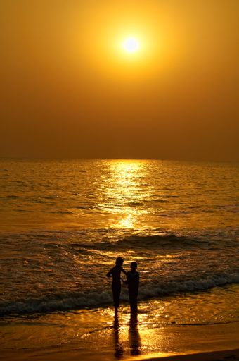 A vertical shot of a silhouette of a couple in the beach