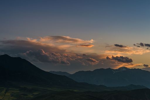 An aerial view of beautiful mountains against a cloudy sky during the sunset in Xinjiang, China