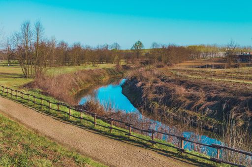 A high angle shot of a river near bushes at Cavour Castle Park, in Italy
