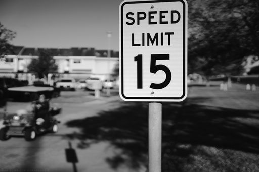 A grayscale shot of a speed limit 15 sign on a street