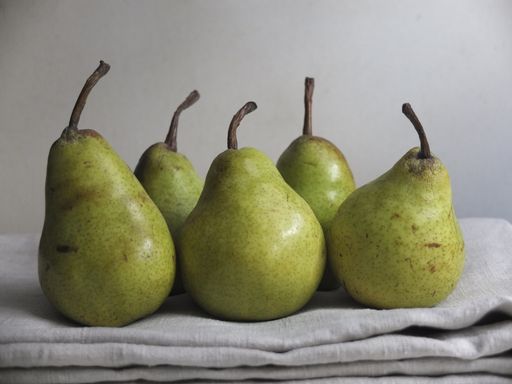 A still life photography of five fresh pears on a white blanket - perfect for a recipe article