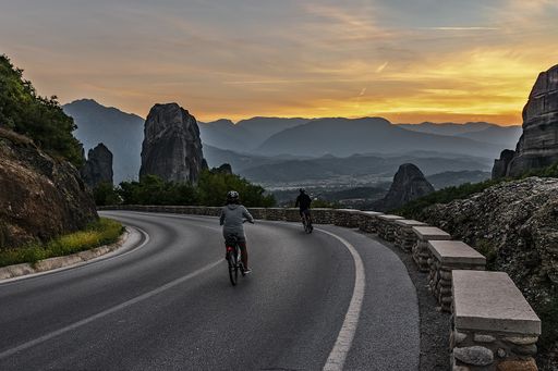 A beautiful shot of two bikers on a road by the cliffs under the amazing sunset in the sky