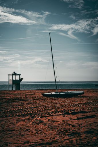 A vertical shot of a boat and a lifeguard tower on the seaside during the daytime - suitable for a wallpaper