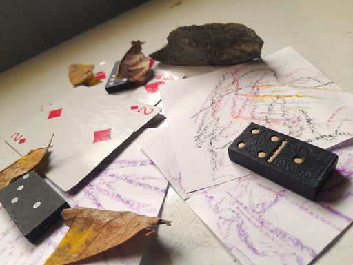 A close-up shot of domino bones on a white table with papers and dry leaves