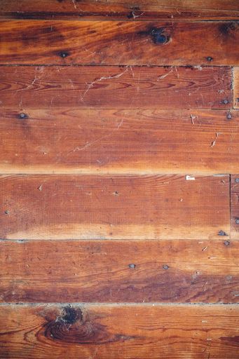 A vertical shot of a wooden background with nails and spiderweb